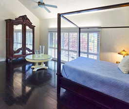 Primary bedroom featuring lofted ceiling, ceiling fan, and hardwood flooring. With view to the East deck and pool.