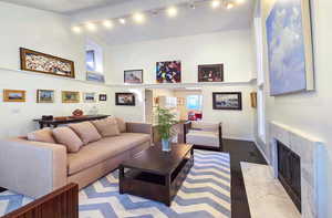 Living room with a towering ceiling and dark wood flooring, featuring a fire place