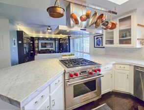 Kitchen featuring stainless steel appliances, white cabinetry, a wealth of natural light, and kitchen peninsula