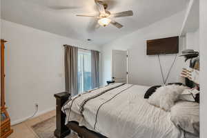 Bedroom with ceiling fan, lofted ceiling, and light tile patterned floors