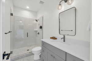 Bathroom featuring an enclosed shower, vanity, and toilet