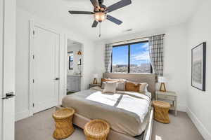 Bedroom with ceiling fan, light colored carpet, and ensuite bath