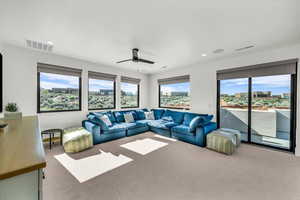 Carpeted living room featuring ceiling fan and a healthy amount of sunlight