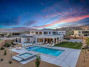 Back house at dusk with a patio, a pool with hot tub, and a mountain view