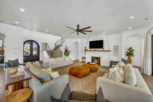 Living room featuring light hardwood / wood-style floors, a fireplace, ceiling fan, and french doors