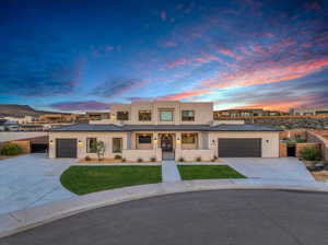 View of front of property featuring a garage and a yard