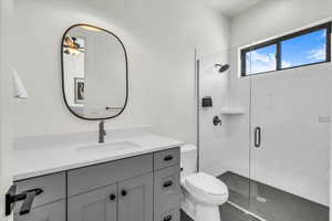 Bathroom with ceiling fan, an enclosed shower, vanity, and toilet