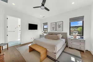 Bedroom with connected bathroom, ceiling fan, and light hardwood / wood-style flooring