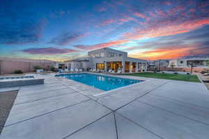 Pool at dusk with an in ground hot tub and a patio