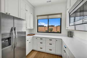 Kitchen featuring appliances with stainless steel finishes, light hardwood / wood-style flooring, and white cabinets