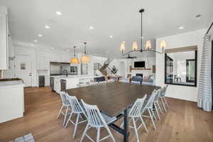 Dining area with ceiling fan with notable chandelier, light hardwood / wood-style floors, and sink