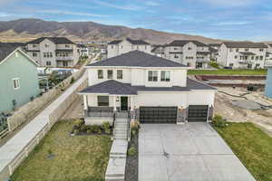 View of front of home featuring a front yard, a mountain view, a garage, and covered porch