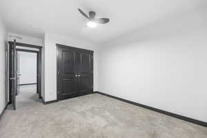 Unfurnished bedroom featuring a closet, ceiling fan, and light colored carpet