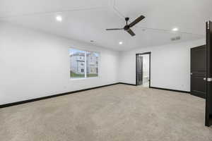 Carpeted empty room featuring vaulted ceiling and ceiling fan