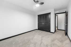 Unfurnished bedroom with a closet, ceiling fan, light colored carpet, and a barn door