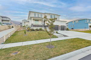 View of front of house featuring a front yard, a garage, and covered porch