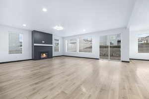 Unfurnished living room with light hardwood / wood-style floors and a large fireplace