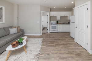 Interior space featuring hardwood / wood-style floors, sink, white appliances, and white cabinetry