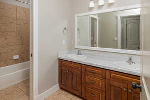 Bathroom featuring tiled shower / bath, vanity, and tile patterned floors