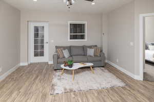 Living room with a textured ceiling, ceiling fan, and hardwood / wood-style flooring