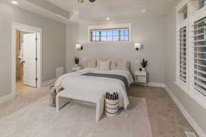 Carpeted bedroom featuring ceiling fan and ensuite bath