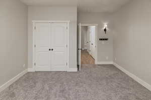 Unfurnished bedroom featuring a closet and light colored carpet