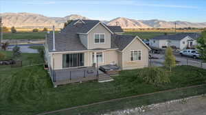 Back of house with a lawn and a deck with mountain view