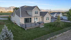 Back of property with a yard and a deck with mountain view