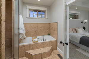 Bathroom featuring plus walk in shower, a wealth of natural light, and tile patterned flooring