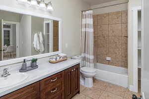 Full bathroom with vanity, tile patterned flooring, shower / tub combo, and toilet