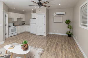 Kitchen with wood-type flooring, white appliances, and white cabinetry