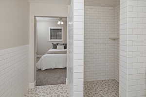 Bathroom with ceiling fan, tile patterned floors, and tiled shower