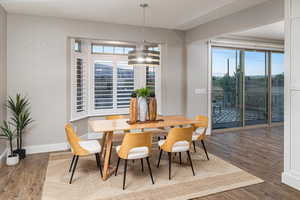 Dining area with a healthy amount of sunlight, dark wood-type flooring, and a notable chandelier