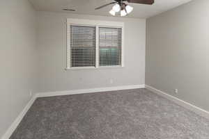 Empty room featuring ceiling fan and carpet floors