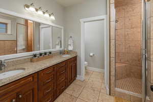 Bathroom featuring vanity, toilet, a shower with door, and tile patterned floors