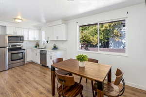 Kitchen featuring light hardwood / wood-style flooring, appliances with stainless steel finishes, sink, and white cabinetry