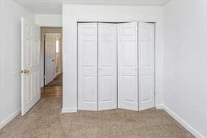 Unfurnished bedroom with light carpet and a closet