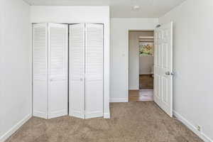 Unfurnished bedroom with light colored carpet and a closet