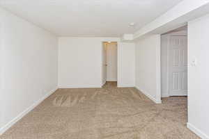 Spare room with a textured ceiling and light carpet