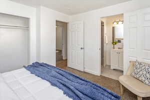 Bedroom featuring ensuite bath, a closet, and light colored carpet