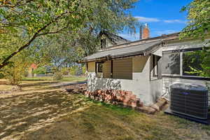 View of side of property with cooling unit and a lawn