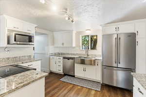 Kitchen featuring stainless steel appliances, white cabinets, dark hardwood / wood-style floors, and sink