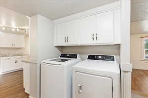 Laundry area with separate washer and dryer, a textured ceiling, and hardwood / wood-style floors