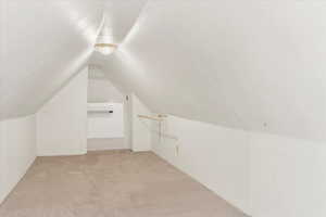 Additional living space with light colored carpet and vaulted ceiling