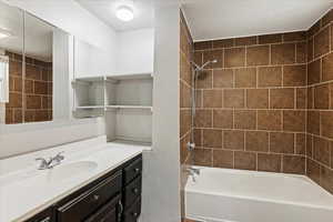 Bathroom with a textured ceiling, vanity, and tiled shower / bath