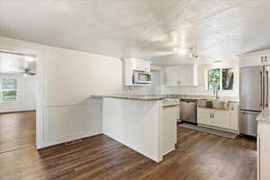 Kitchen featuring light stone counters, sink, white cabinetry, stainless steel appliances, and dark hardwood / wood-style flooring