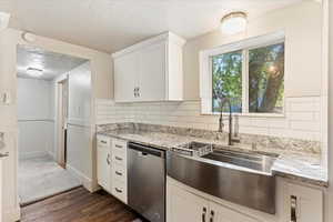 Kitchen featuring white cabinets, tasteful backsplash, dishwasher, dark hardwood / wood-style flooring, and a textured ceiling