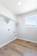 Laundry area with hookup for a washing machine, light wood-type flooring, and electric dryer hookup