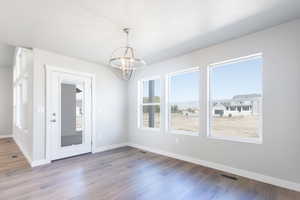 Unfurnished dining area with hardwood / wood-style floors and a chandelier