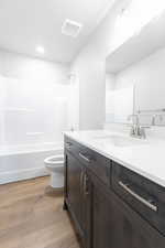 Full bathroom with bathtub / shower combination, hardwood / wood-style floors, vanity, and toilet